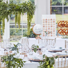 Gedekte tafel voor bruiloft met botanische decoratie en een wereldbol