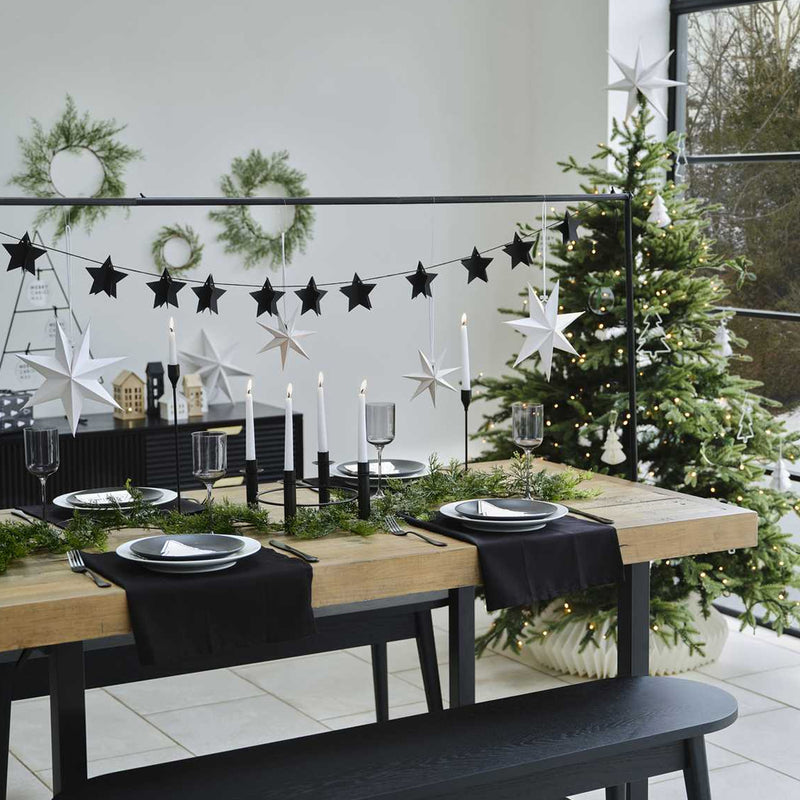 Gedekte tafel met standaard erboven met een sterrenslinger eraan en een kerstboom
