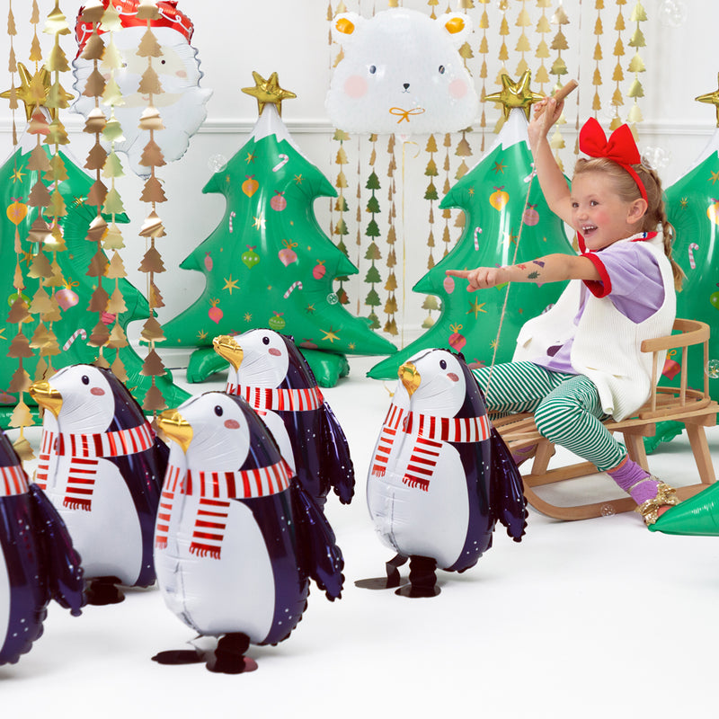 Kind met kerstdecoratie zoals pinguin en kerstboom folie balonnen