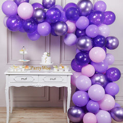 Kamer met witte brocante hapjes tafel en paarse boog van ballonen
