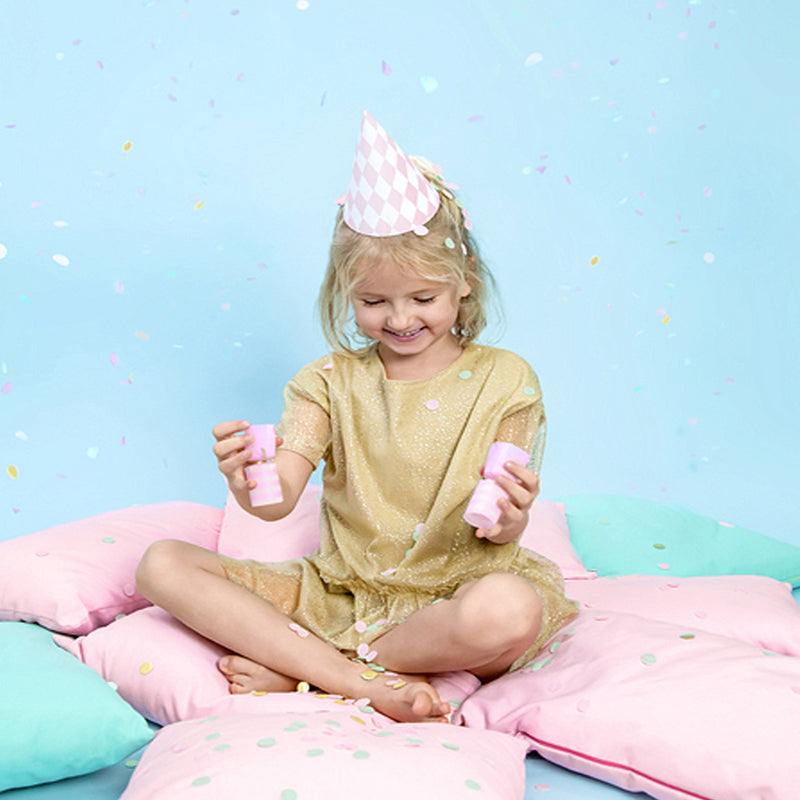 kind zit op kussens op de grond met confetti