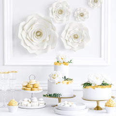 Gedekte hapjes tafel met witte en gouden decoratie taart en macarons