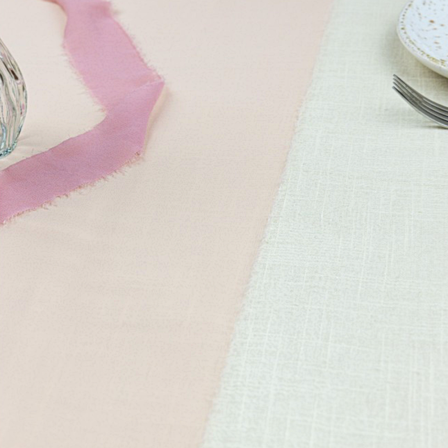 Poeder roze tafelloper ligt op een wit kleed van katoen