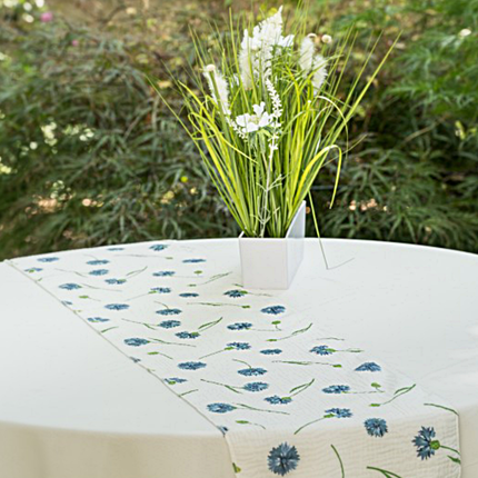 tafelloper met blauwe bloemen ligt op een wit tafelkleed