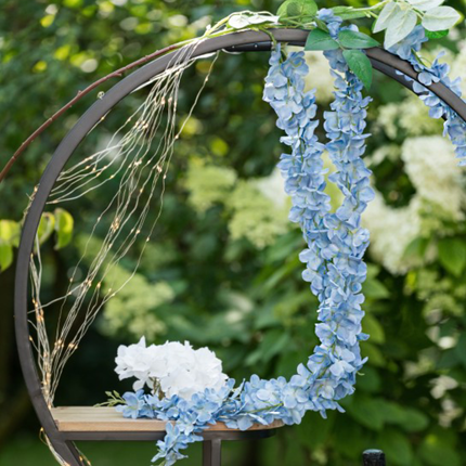 blauwe bloemslinger hangt aan een zwart metalen prieel