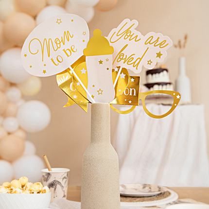 Gouden en beige photo booth props voor een babyshower zitten in een vaasje