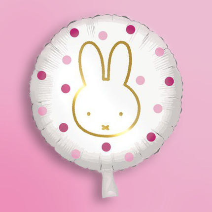 Ronde folieballon met roze stippen en nijntje erop op een roze achtergrond