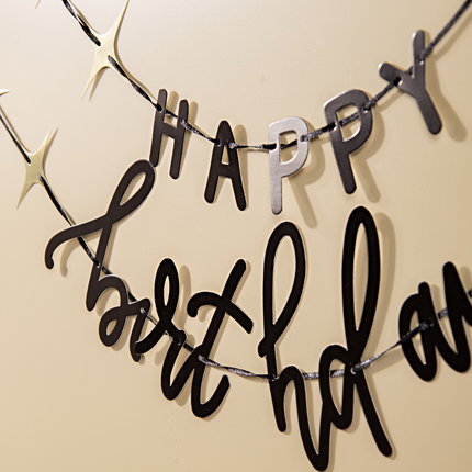 zwarte slinger met de tekst happy birthday en gouden sterren