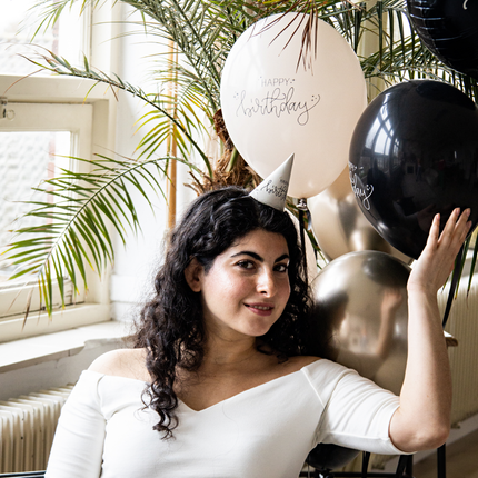 vrouw met een zwarte en creme ballon met de tekst happy birthday