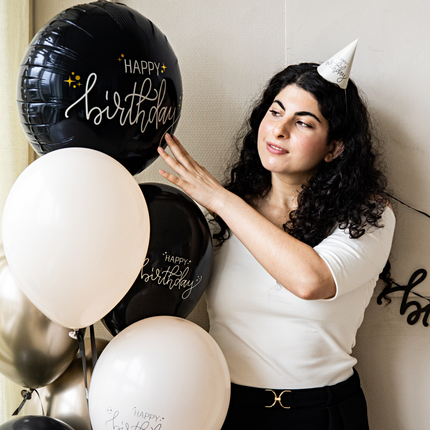 vrouw met zwarte krullen en een tros creme en zwarte ballonnen