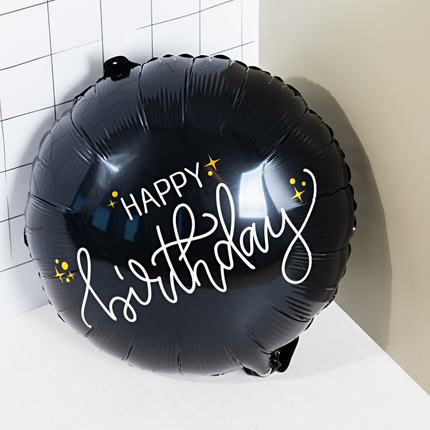 zwarte ballon met de witte tekst happy birthday en gouden sterren