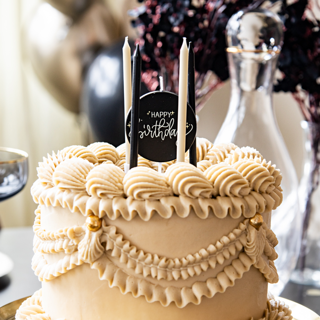bruine taart met creme, beige en zwarte kaarsjes
