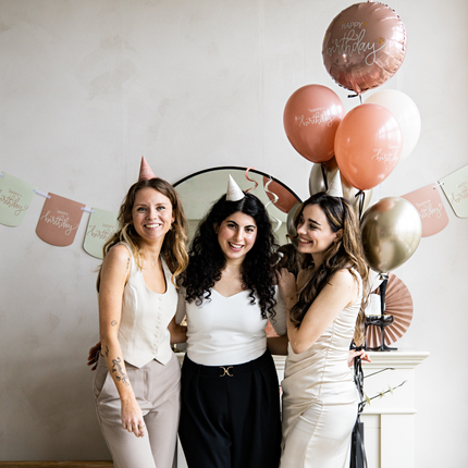 drie vrouwen op een verjaardag versierd met creme, roze en gouden versiering
