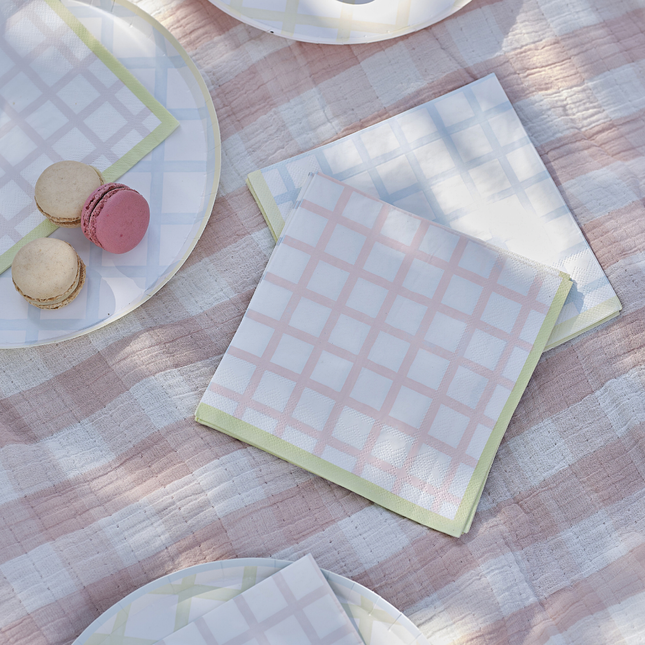 Servetten met geblokte print in het roze, groen, blauw en geel liggen op een roze geblokt kleed