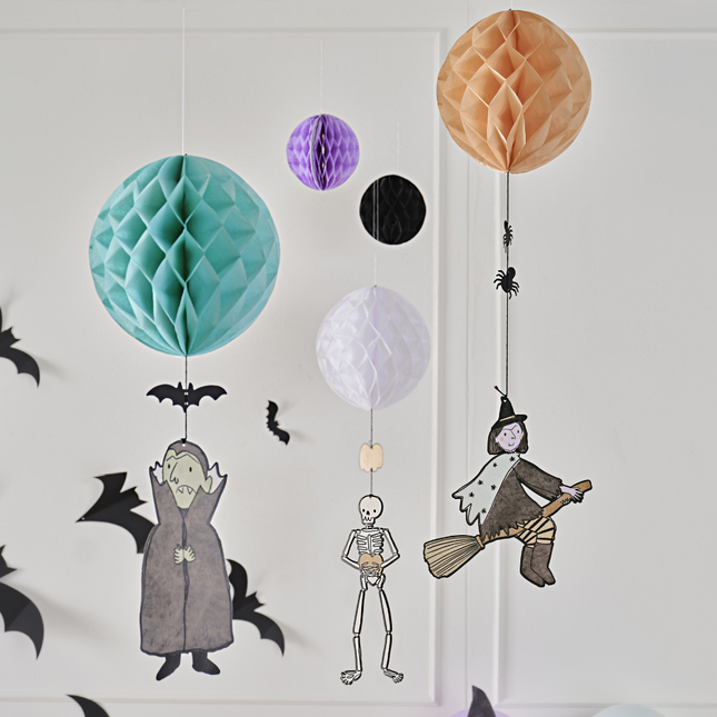 Honeycombs in het oranje, mint, paars, wit en zwart met versieringen eronder zoals een heks, vampier, vleermuis of spinnetjes hangen voor een witte muur