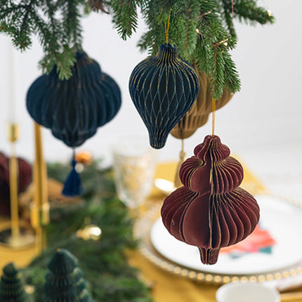 drie papieren hangers in verschillende kleuren en vormen boven een gedekte tafel