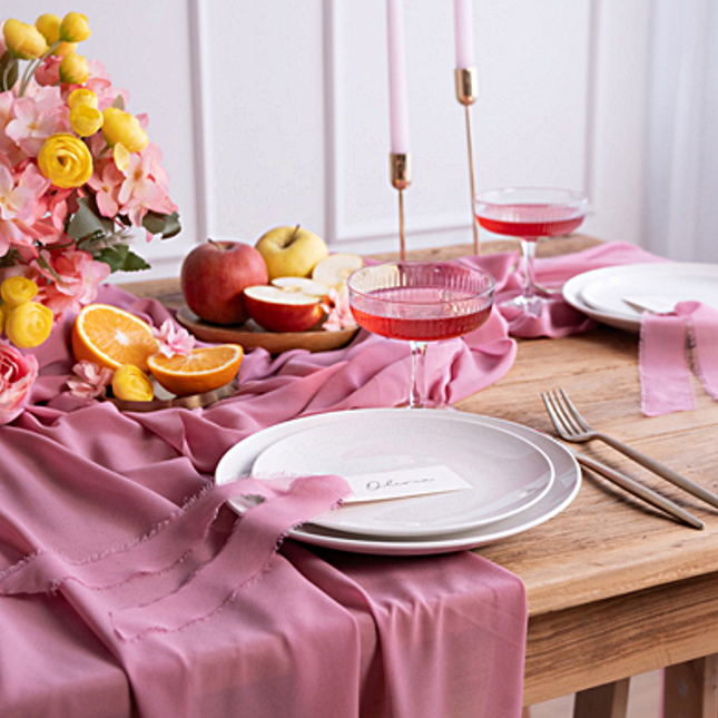 donkerroze tafelloper op een houten tafel met gele kunstbloemen