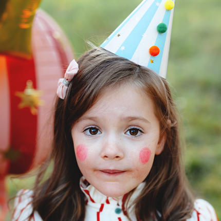 meisje geschminkt als clown met een feesthoedje op