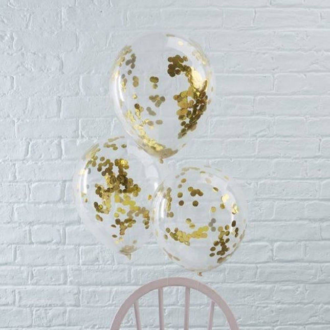 Drie confetti ballonnen gevuld met gouden confetti bevestigd aan een stoel