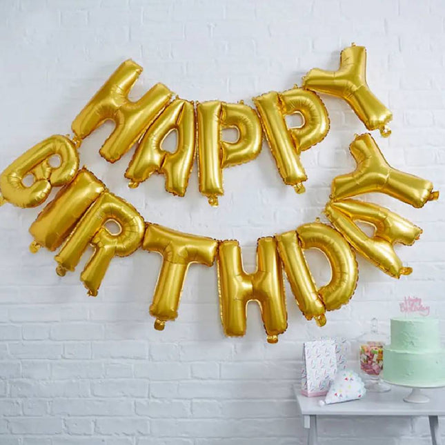 Folie ballon in de vorm van de woorden Happy birthday aan de muur