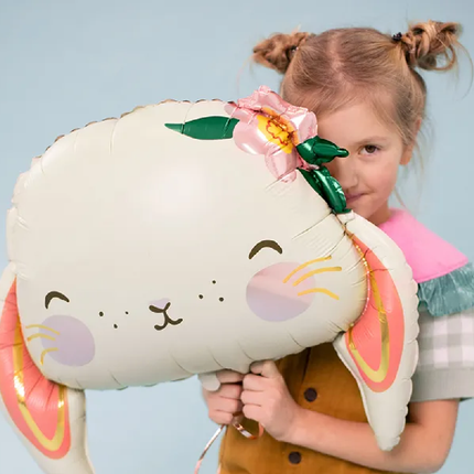 Meisje met twee knotjes houdt een folieballon vast in de vorm van een konijn met lichtoranje en gouden kleuren