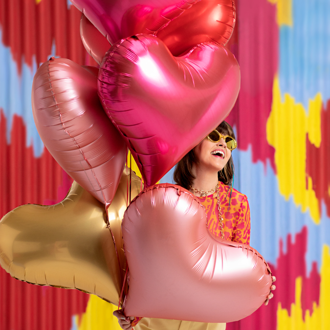 Vrouw met hartvormige ballonnen in het roze, rood en goud