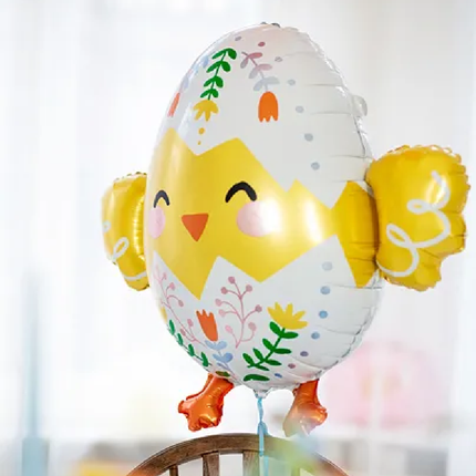 Folieballon in de vorm van een kuiken zweeft boven de stoel