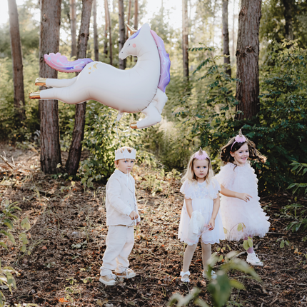 drie kinderen spelen in een bos met een grote eenhoorn ballon