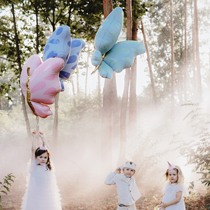 drie kinderen spelen in een bos met drie vlinder ballonnen in het blauw, mint en roze