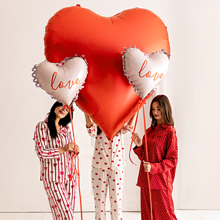 vrouwen in hartjes pyjama's bij folieballonnen in de vorm van hartjes