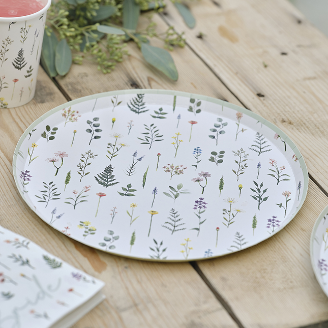 Bordje versierd met bloemen en planten ligt op een houten tafel