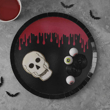 Zwart bordje met rode bloeddruppels erop en halloween snoep