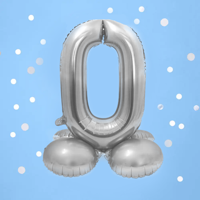 Foliecijfer 0 in het zilver op standaard op een blauw achtergrond met witte confetti