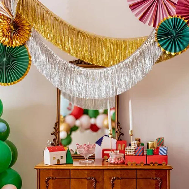 Zilveren en gouden slingers boven een bruin kastje met kerstversiering