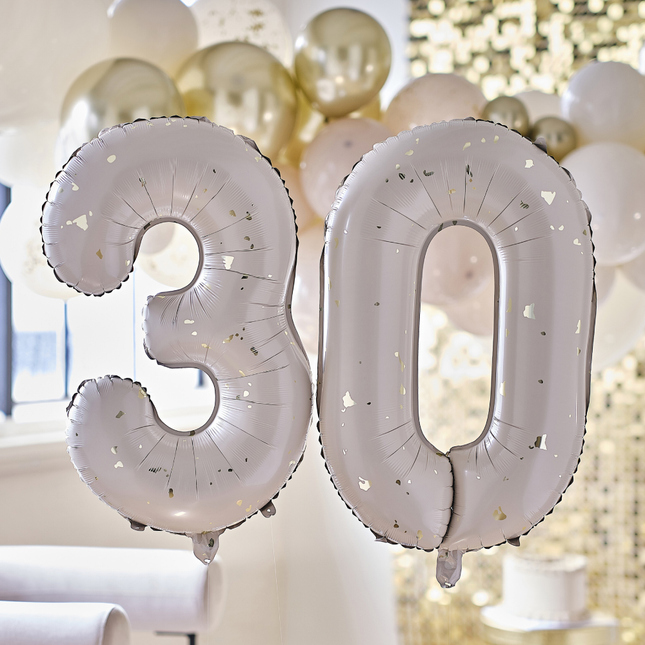 Cijferballonnen 30 in het nude met gouden spikkels hangt voor een ballonnenboog en gouden backdrop