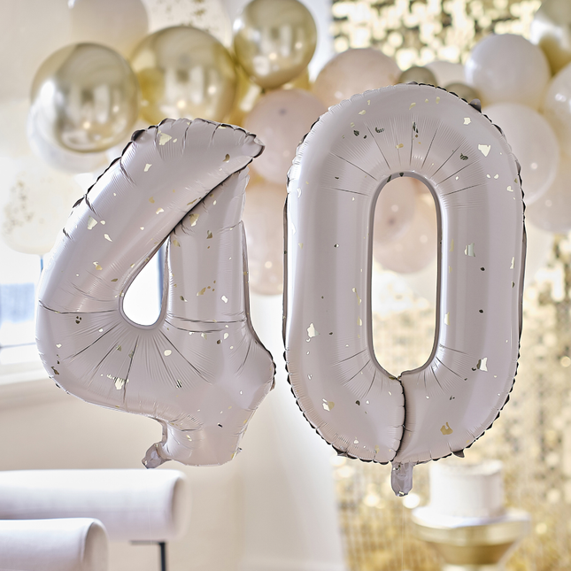 Cijferballonnen 40 in het nude met gouden spikkels hangt voor een ballonnenboog en gouden backdrop