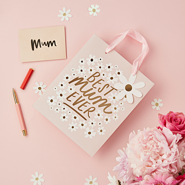 Roze cadeautasje met de gouden tekst best mum ever en madeliefjes ligt op een roze ondergrond