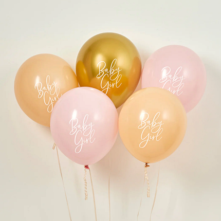 Set ballonnen in het goud, nude en lichtroze met de witte tekst baby girl op een beige muur