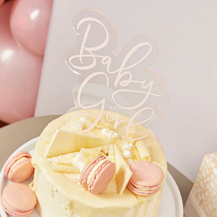acryl taart topper met roze tekst baby girl in een beige taart met macarons die er best lekker uit ziet