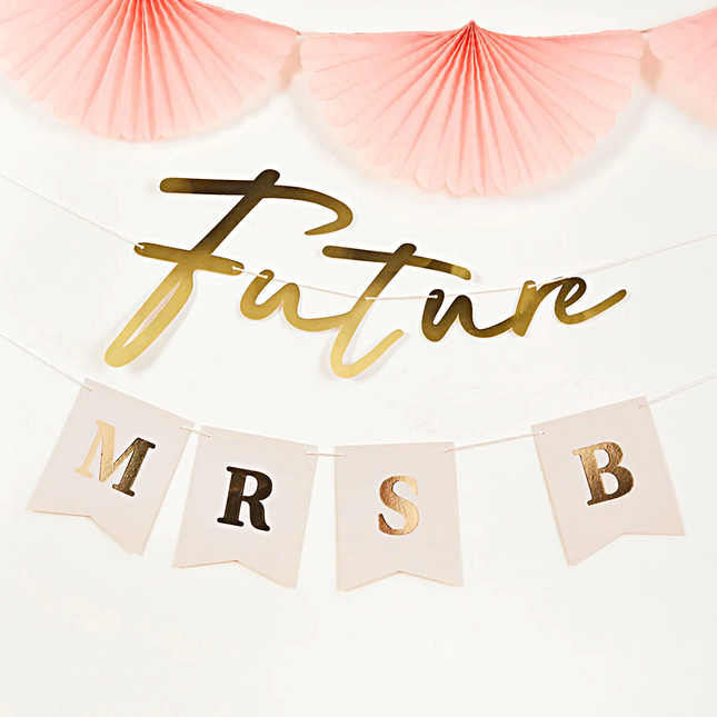 personaliseerbare letterslinger in het goud en perzik met de tekst futuure mrs hangt onder roze waaiers