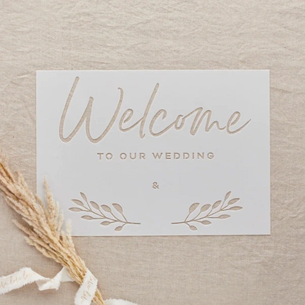 transparant stencil met de tekst welcome to our wedding op een jute achtergrond met graan