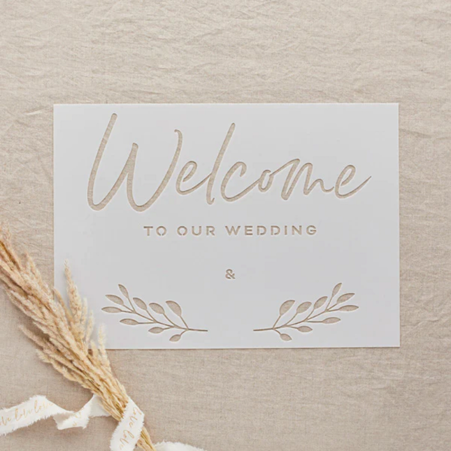 transparant stencil met de tekst welcome to our wedding op een jute achtergrond met graan