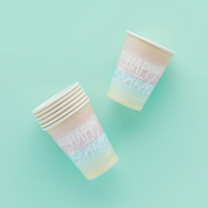 Pastelkleurige regenboogbekers met witte tekst happy birthday op een mintgroene achtergrond