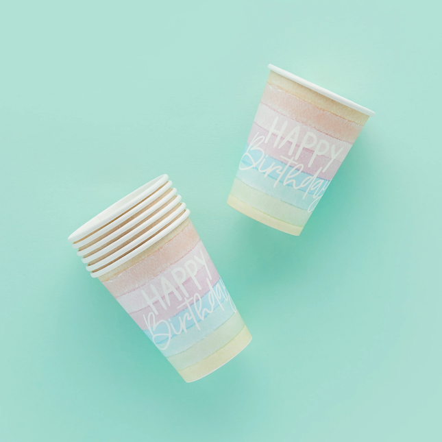 Pastelkleurige regenboogbekers met witte tekst happy birthday op een mintgroene achtergrond