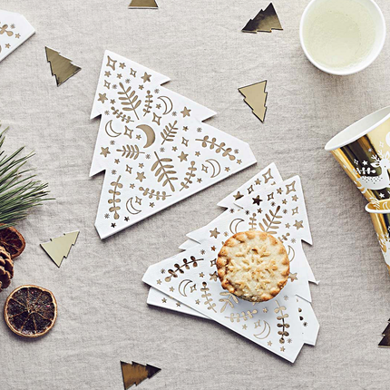 Servetten in de vorm van een kerstboom met goudenprint liggen op een katoenen beige kleed