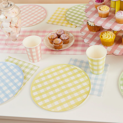 tafel versierd met geblokte items zoals servetten, bordjes en bekers in het geel, groen, roze en blauw