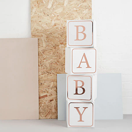 Witte blokken met rose gouden tekst baby voor een schuimen bord en lichtroze plaat