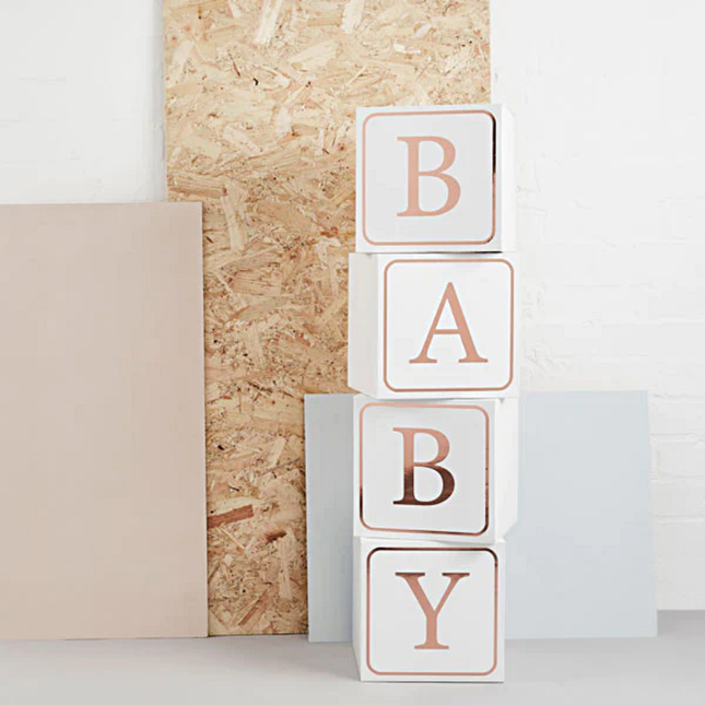 Witte blokken met rose gouden tekst baby voor een schuimen bord en lichtroze plaat