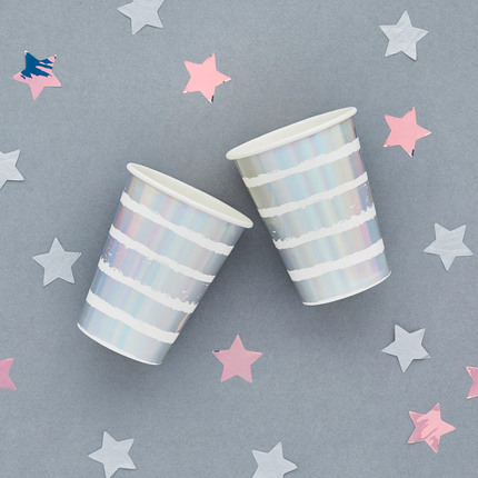 iridescent en wit gestreepte bekers op een grijze achtergrond met holofragrafische sterren confetti