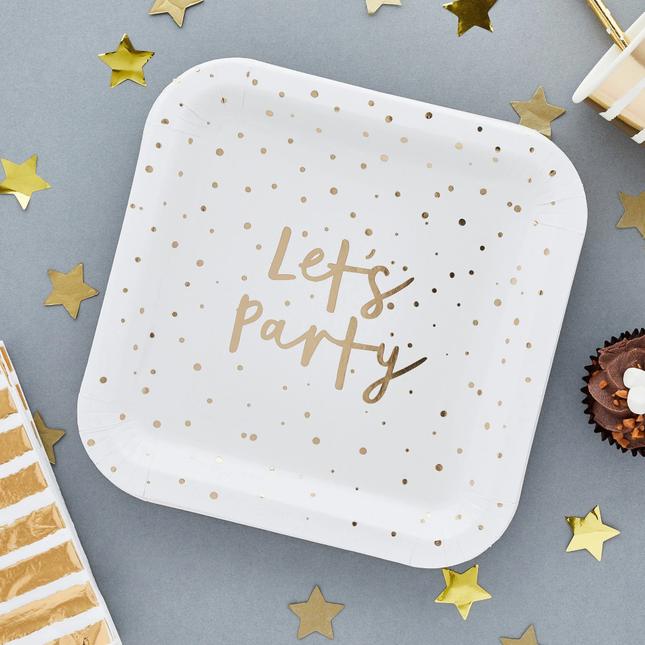 witte vierkante bordjes met gouden stippen en gouden tekst lets party ligt naast gouden ster confetti